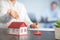 Businesswoman choosing mini house model from model on wood table