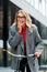 Businesswoman in coat and glasses smiling and riding bike