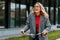 Businesswoman in coat and glasses smiling and riding bike