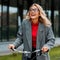 Businesswoman in coat and glasses smiling and riding bike