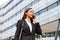 Businesswoman Commuting To Work Talking On Mobile Phone Outside Modern Office Building