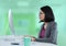 Businesswoman with computer at desk with bright green background