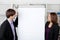 Businesswoman With Coworker Looking At Flip Chart