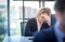 A businesswoman with curly blonde hair resting her hands on her head