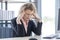 A businesswoman with curly blonde hair resting her hands on her head, feeling anxious, serious and tired