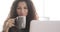 Businesswoman drinking coffee and video chatting using office laptop