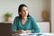 Businesswoman With Earbuds Receiving Call Taking Notes Sitting In Office