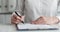 Businesswoman examines document and puts signature closeup