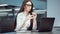 Businesswoman in eyeglasses working on laptop and writing in journal