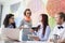 Businesswoman giving coffee to female colleague in creative office