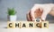 Businesswoman hand holding wooden cube with flip over block CHANGE to CHANCE word on table background. success, strategy