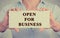 Businesswoman hands holding white sign with message open for business