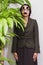 Businesswoman hiding behind plant wearing disguise