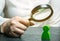 Businesswoman is holding a magnifying glass over a green man figure. Search for a talented employee. Identifying strengths in the