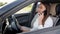 Businesswoman with long hair talks on smartphone driving car