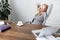 businesswoman lying on chair with hands behind head coffee cup