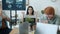 Businesswoman meditating in office while joyful colleagues throwing paper balls having fun