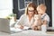 Businesswoman mother woman with toddler working at computer