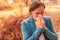 Businesswoman nose-blowing paper tissue in autumnal park