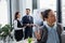 Businesswoman with notebook standing near colleagues