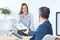 businesswoman passing clipboard with documents to partner