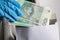 Businesswoman in a protective mask and protective gloves puts a bundle of paper banknotes into the envelope