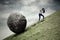 Businesswoman pulling stone on the hill