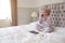 Businesswoman In Pyjamas Sitting On Bed Making Call On Mobile Phone Working From Home