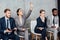 Businesswoman raising hand while focused multiethnic businesspeople sitting on chairs