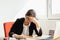 Businesswoman resting hands on head with eyes close at work desk in office.