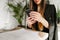 Businesswoman sits in a cafe with business papers and a cup of coffee, uses a smartphone. Formal woman uses internet on smartphone