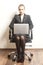 Businesswoman sits on chair with her laptop on wallpaper background