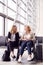 Businesswoman Sitting In Airport Departure With Female Colleague In Wheelchair Talking Together