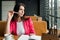 Businesswoman is sitting in a cafe thinking about something. Lunch time portrait of serious young entrepreneur lawyer in a pink