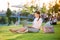 Businesswoman sitting in park working on laptop, sunny summer da