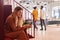 Businesswoman Sitting By Stairs In Modern Open Plan Office Checking Messages On Mobile Phone