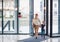 A businesswoman with small daughter entering office building, walking.