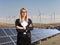 Businesswoman on a solar panel field with wind turbines