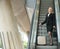 Businesswoman standing on escalator with luggage