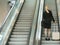Businesswoman standing on escalator with travel bags