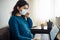 Businesswoman stays home and works during coronavirus epidemia quarantine. Female worker touches her medical mask and typing on a