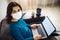 Businesswoman stays home and works during coronavirus epidemia quarantine. Female worker wearing a medical mask and typing on a
