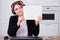 Businesswoman in a suit with a blank sheet in her hands during an online conference, copy space. A woman with headphones holds a