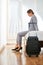 Businesswoman with suitcase sitting on bed