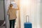 Businesswoman traveller standing in hotel room by window with sunlight through curtain