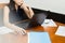 Businesswoman using computer mouse working on laptop with paperwork on table.