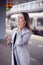 Businesswoman Waiting On Train Platform With Wireless Earbuds Answers Call On Mobile Phone