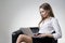 Businesswoman in a white blouse sitting in a leather armchair with her laptop.