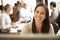 Businesswoman Working At Desk With Meeting In Background