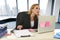 Businesswoman working at laptop computer sitting on the desk absent minded